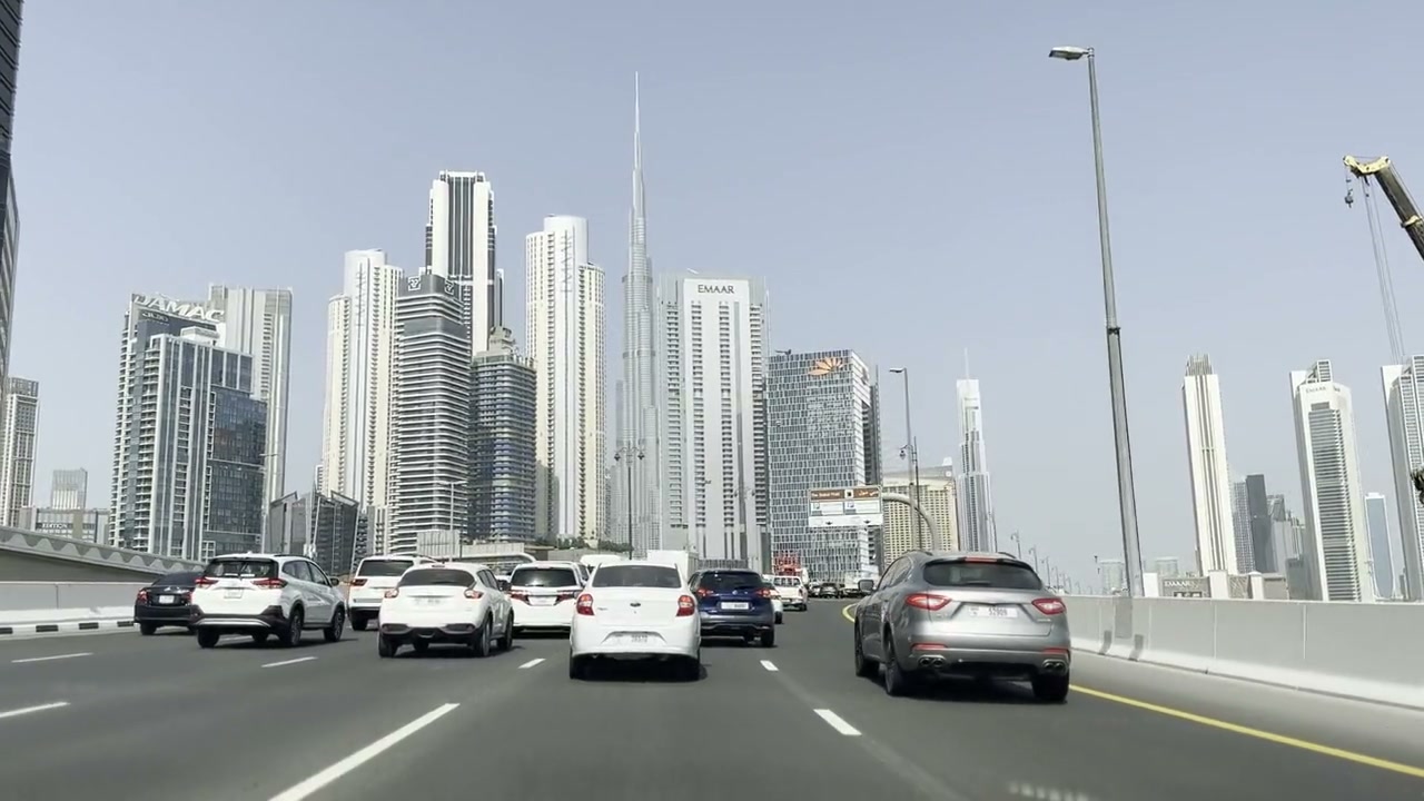 Downtown Dubai financial district with the Burj Khalifa and traffic flowing past EMAAR towers